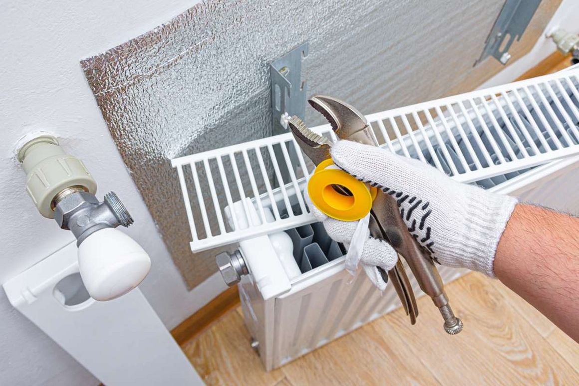 Eine Person montiert einen Heizkörper mit Zange und Dichtungsband.